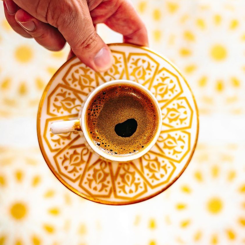 Traditional Middle Eastern coffee cup on a gold patterned saucer