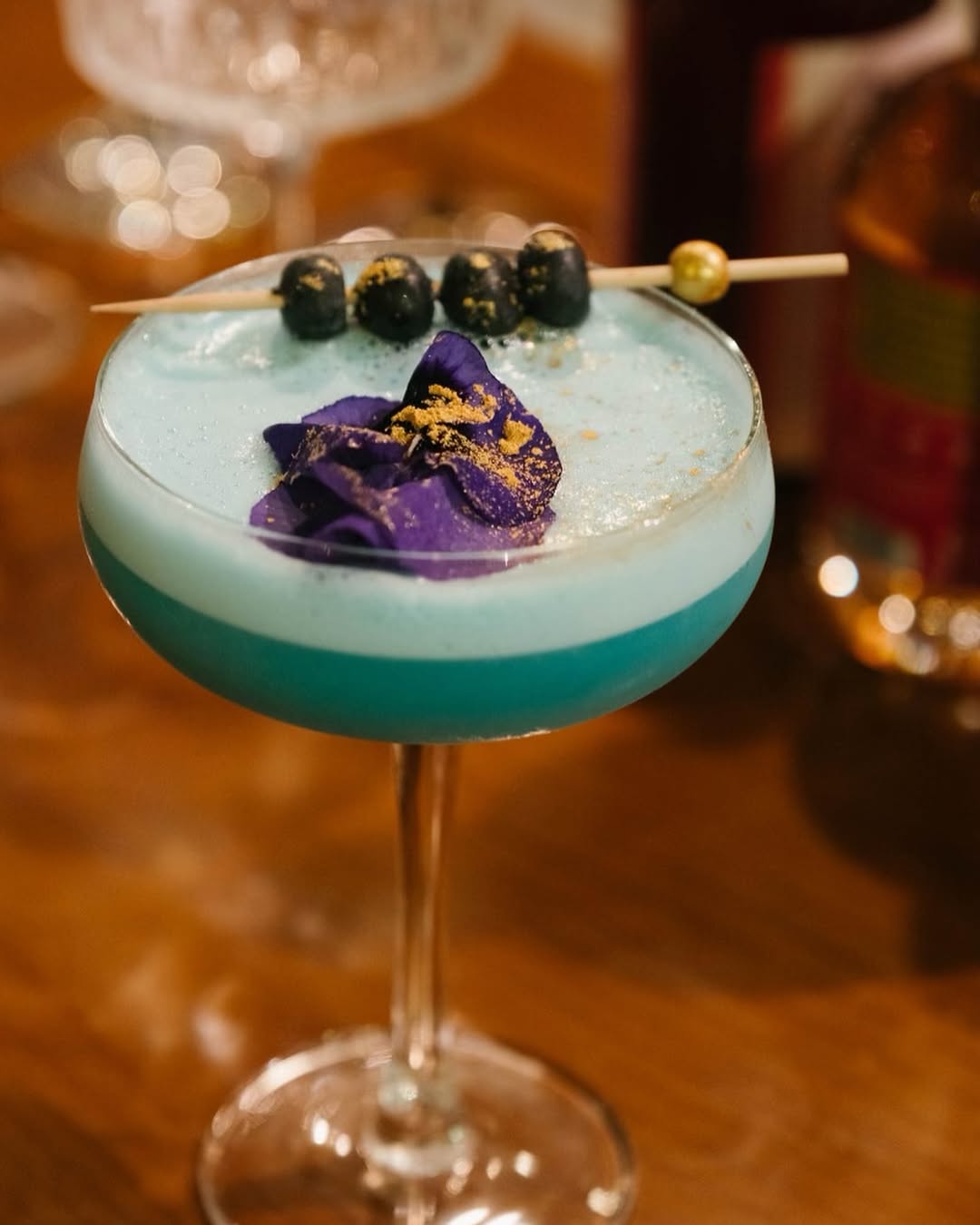 Blue dessert drink with edible flowers and gold garnish